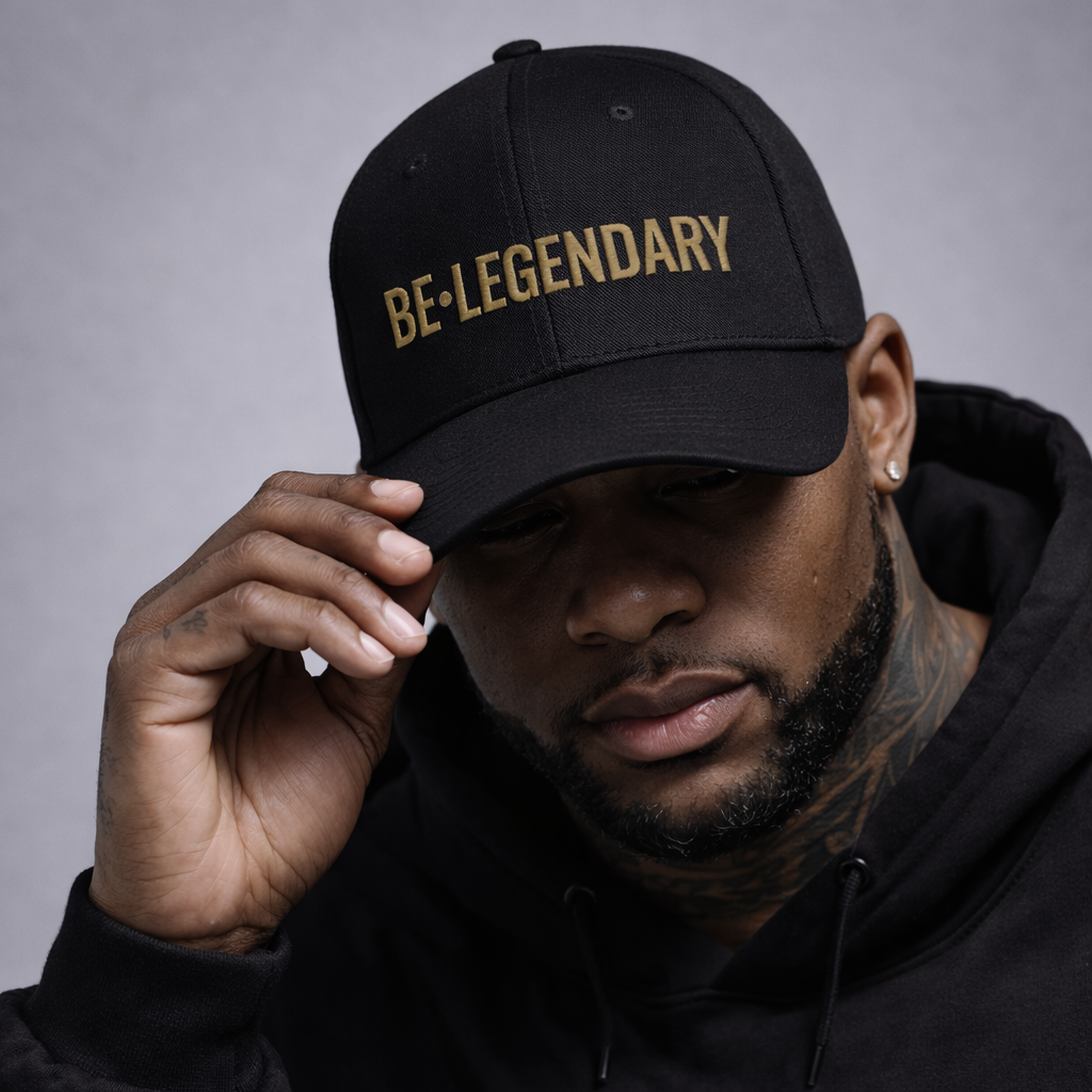 Man wearing a black cap with 'BE•LEGENDARY' text, posing against a gray background