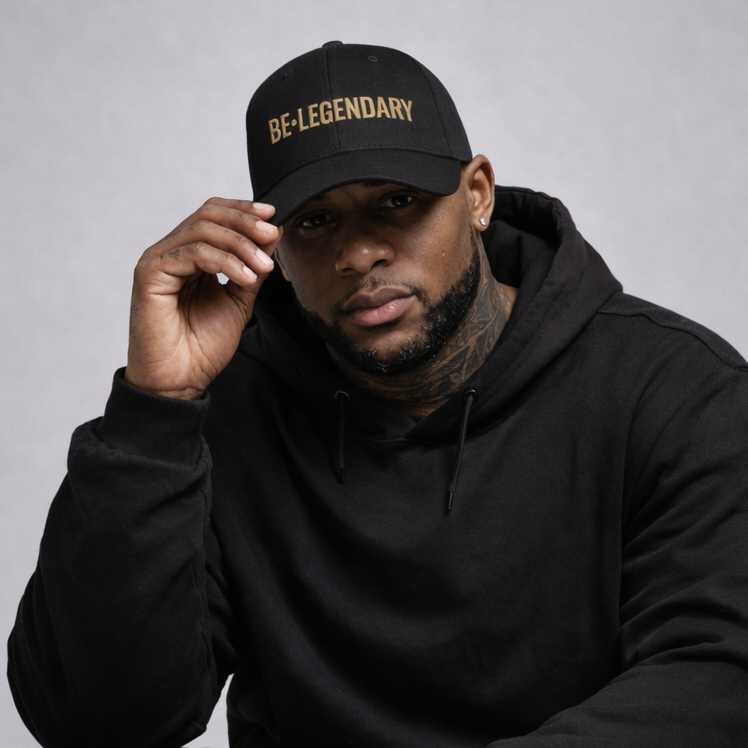 Man wearing a black cap with 'BE•LEGENDARY' text and a black hoodie on a gray background
