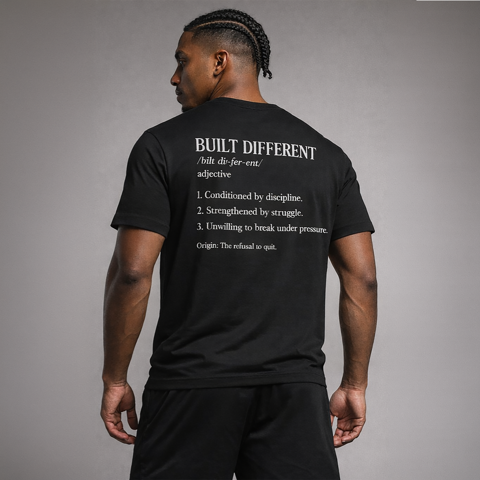 Man wearing a black t-shirt with text on the back against a gray background