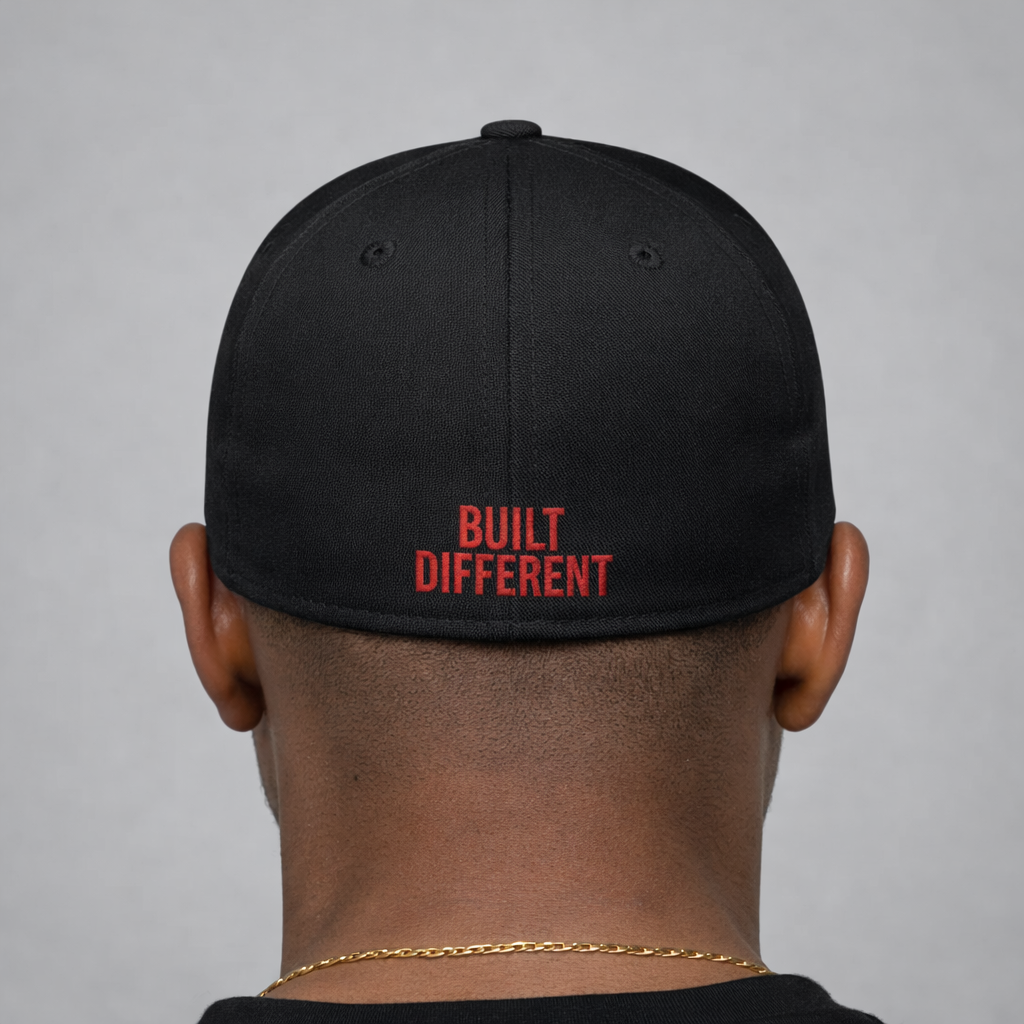 Black cap with 'BUILT DIFFERENT' text on the back, worn by a person against a gray background
